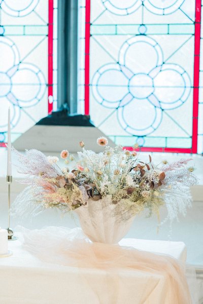 Candles lit on table in front of window flowers setting church tinted