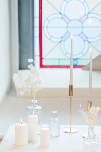 Candles lit on table in front of window flowers setting church tinted