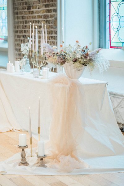 Candles lit on table in front of window flowers setting church tinted bouquet