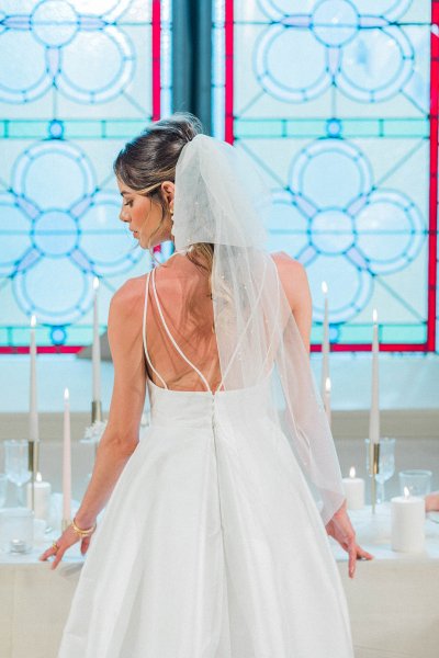 Bride standing at table hand veil detail candle behind hair shot veil