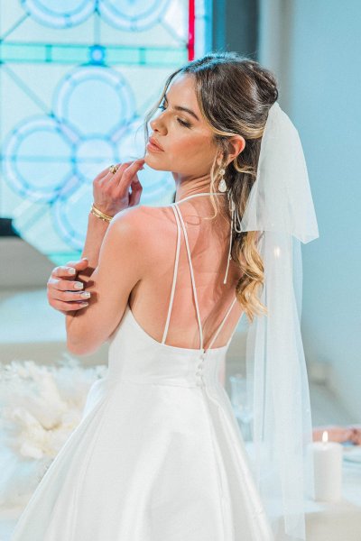 Bride standing at table hand veil detail candle behind hair shot