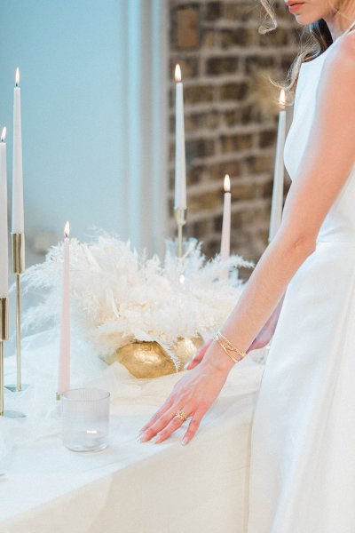 Bride standing at table hand veil detail candle