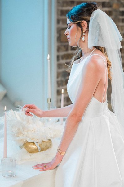 Bride standing at table hand veil detail candle