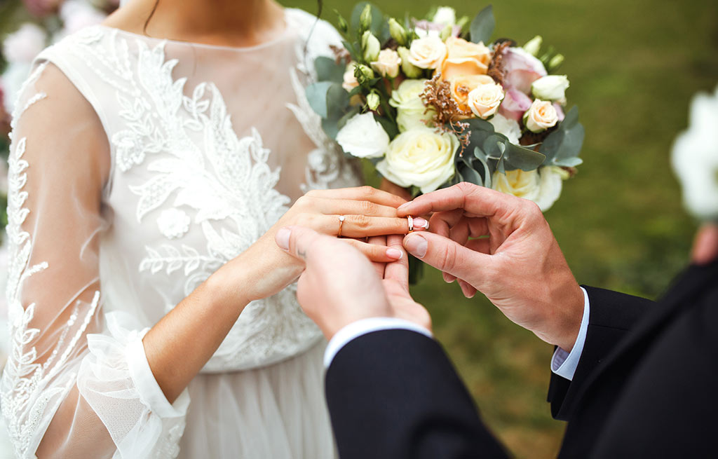 Groom puts wedding ring/band on brides finger