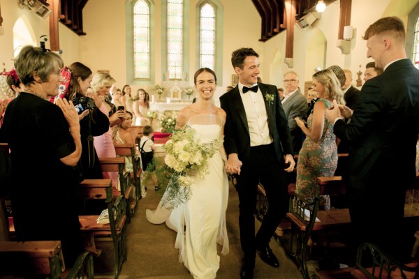 Guests clap at bride and groom exit church just wed