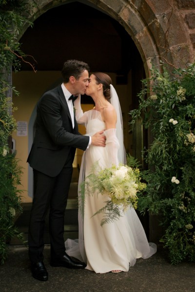 Bride and groom just wed at church entrance kissing kiss