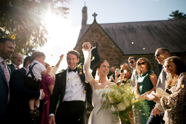 Bride and groom celebrate just wed moment with guests throwing confetti over them