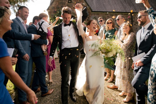 Bride and groom celebrate just wed moment with guests throwing confetti over them