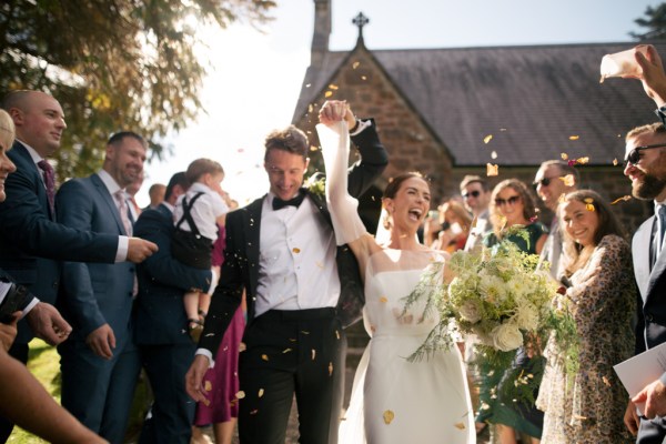 Bride and groom celebrate just wed moment with guests throwing confetti over them