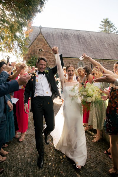 Bride and groom celebrate just wed moment with guests throwing confetti over them