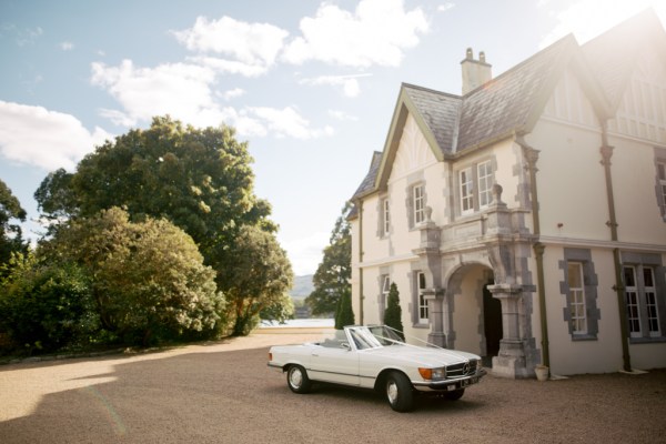 White wedding car parked up beside entrance to wedding venue