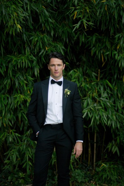 Groom standing in front of tree in garden