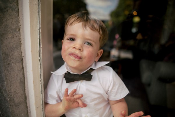 Little boy with bow tie squishes his face against window