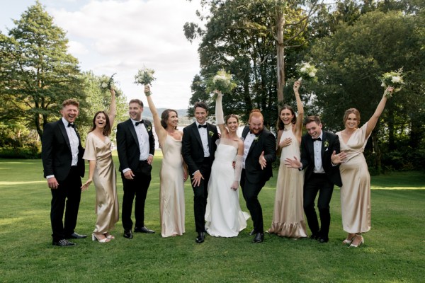 Group photo groom bride groomsmen and bridesmaids celebrate on grass flowers in the air