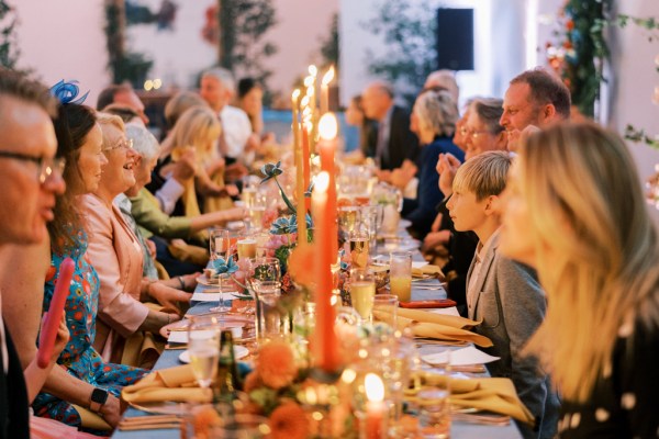 Guests sit at table talking laughing candles are lit