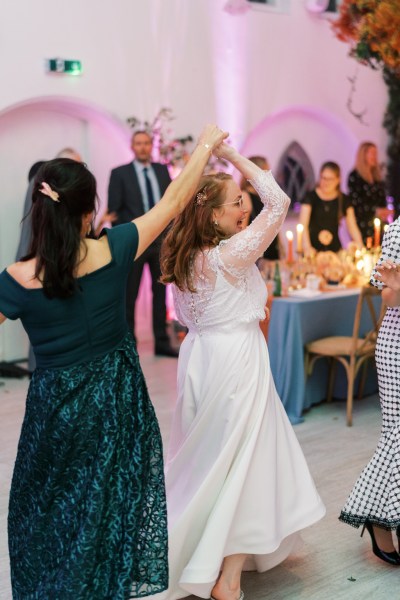 Bride dancing on the dancefloor with guests with woman