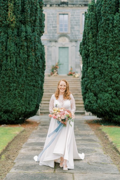 Bride on her own standing holding bouquet flowers in garden