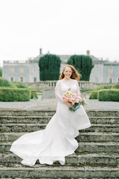 Bride holding bouquet roses flowers standing on steps in front of venue