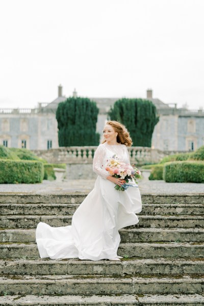 Bride holding bouquet roses flowers standing on steps in front of venue