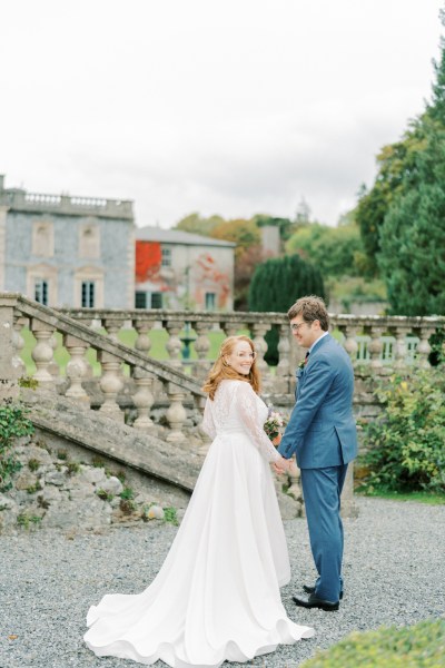 Bride and groom look at each other holding hands in garden