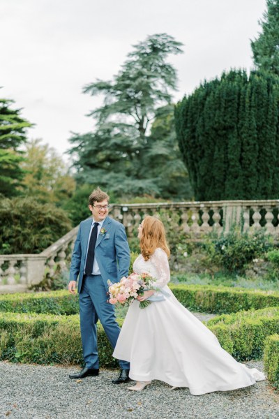 Bride and groom look at each other holding hands in garden