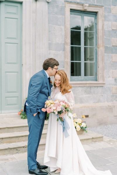 Bride and groom kiss on the forehead exterior bouquet