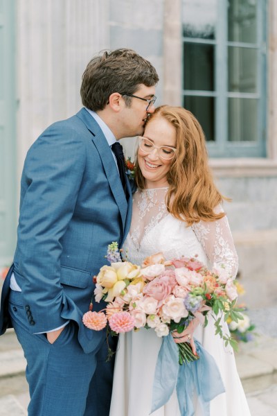 Bride and groom kiss on the forehead exterior bouquet