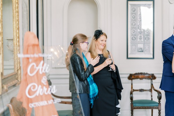 Two women in black standing drinking talking