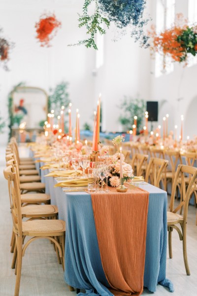 Empty dining room setting orange and blue pink flowers bouquet candles lit atmosphere