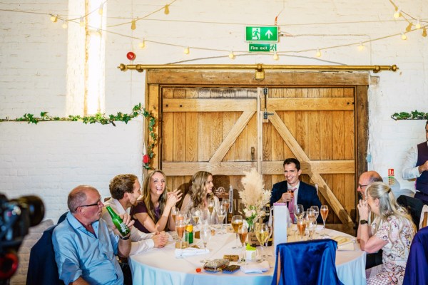 Man gives speech groom bride laughing smiling at table