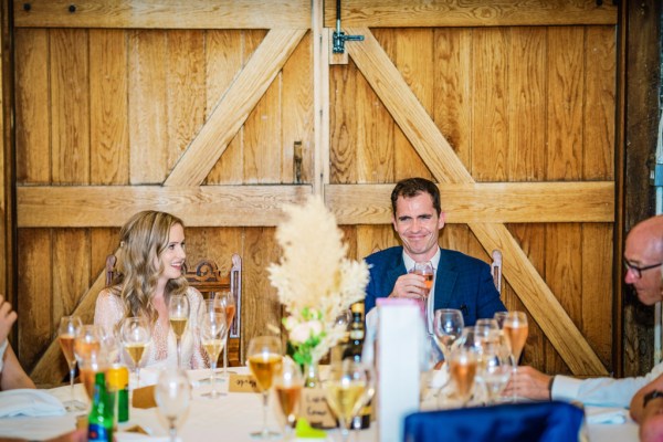 Man gives speech groom bride laughing smiling at table