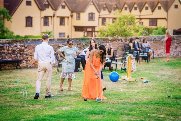 Woman in orange dress playing Polo on the grass in garden