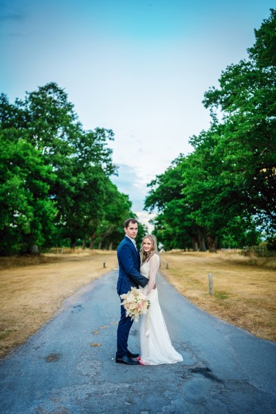 Bride and groom stand in a forest garden park posing for camera