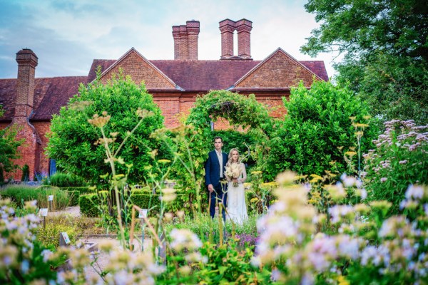 Bride and groom standing in garden flowers surrounding them