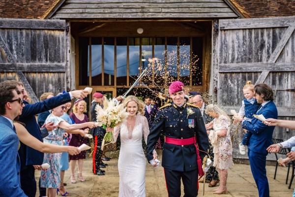 Swords over couples heads bride and groom and guests throwing confetti