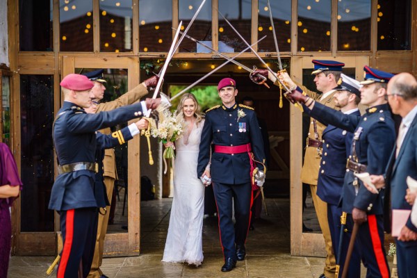 Swords over couples heads bride and groom and guests throwing confetti