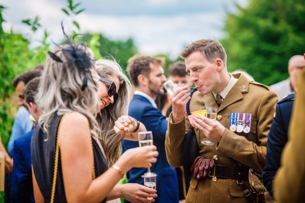 Man in soldier outside militia wear drinking champagne with guests and woman