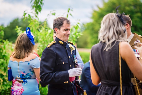 Man in soldier outside militia wear drinking champagne with guests