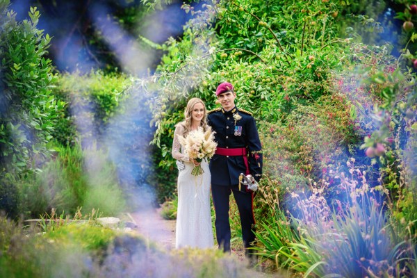 Bride and groom wearing soldier outfit in garden sword and flowers bouquet