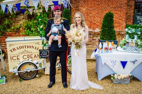 Bride and groom holding baby and flowers in arms hands