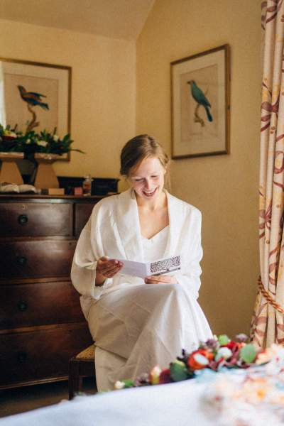 Bride smiling as she reads the letter card note from groom