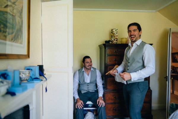 Groom and groomsman laughing getting ready before wedding