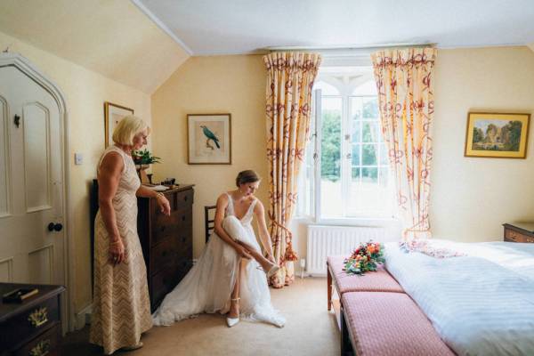 Bride putting on white wedding heels/shoes getting ready in room