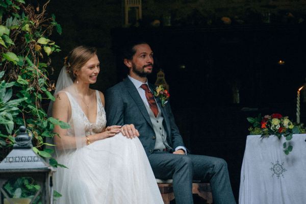 Bride and groom sitting whilst officiant gives speech