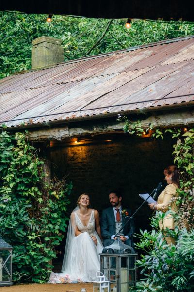 Bride and groom sitting whilst officiant gives speech