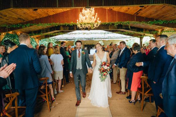 Bride and groom hand shake exiting ceremony guests clapping