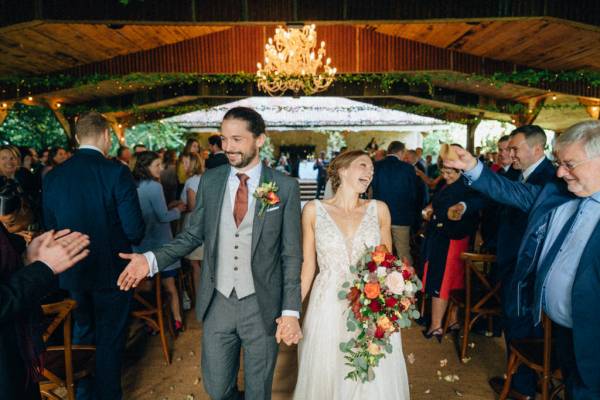 Bride and groom hand shake exiting ceremony guests clapping