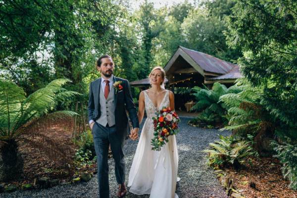 Bride and groom in the garden walking and holding hands