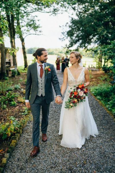 Bride and groom in the garden walking and holding hands