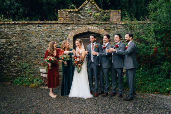 Bride bridesmaids pose for a picture in garden with groom and groomsmen